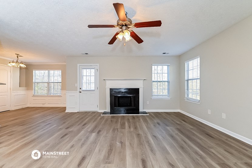 an empty living room with a fireplace and a ceiling fan