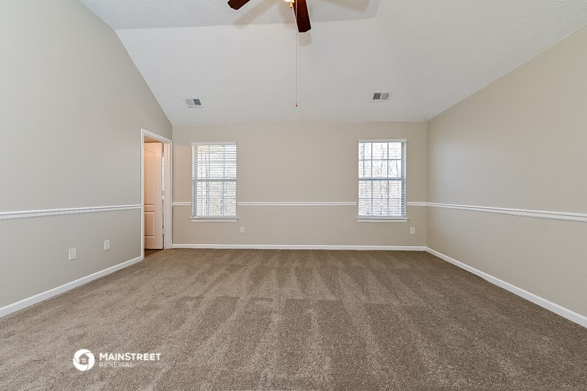 an empty living room with carpet and a ceiling fan
