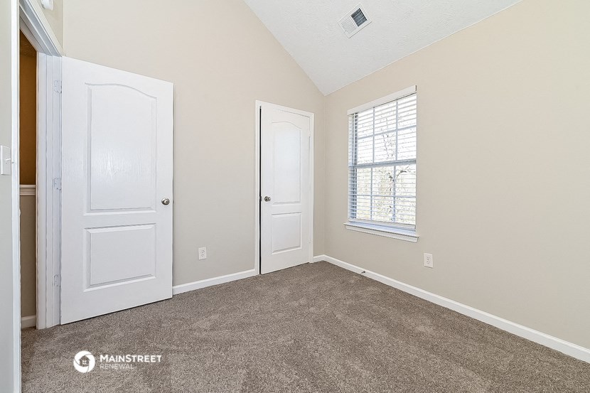 an empty bedroom with two doors and a window