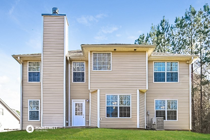 an apartment building with tan siding and a green lawn