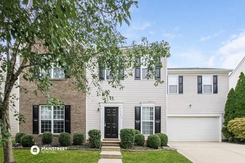 a white house with black shutters and a tree in front of it