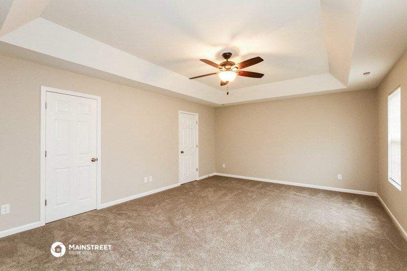 the spacious living room with ceiling fan and carpet