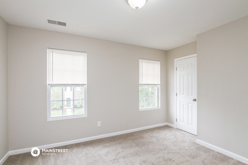 an empty room with a door and two windows
