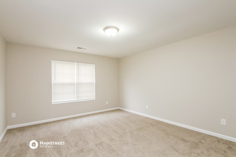 the spacious living room with carpeting and a window