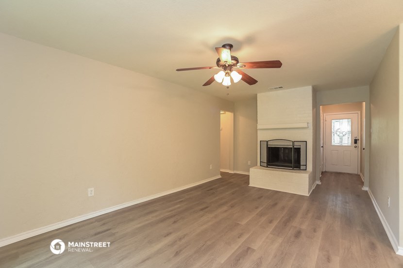the spacious living room with fireplace and ceiling fan