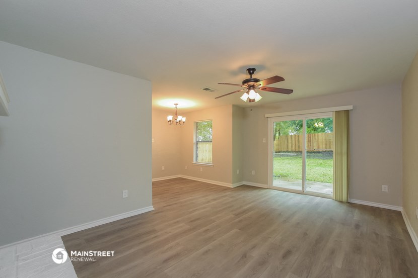 an empty living room with a ceiling fan and a window