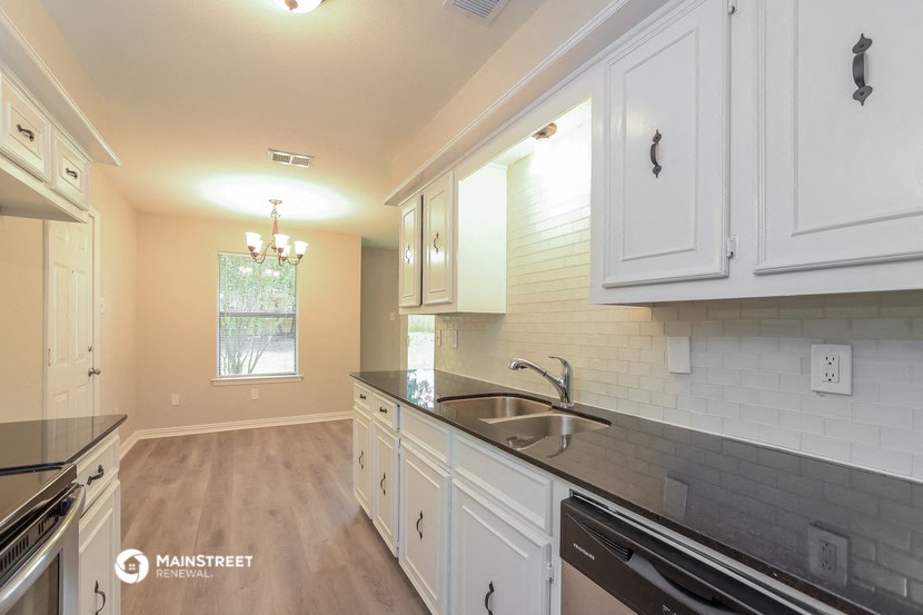 a kitchen with white cabinets and a black counter top and a sink