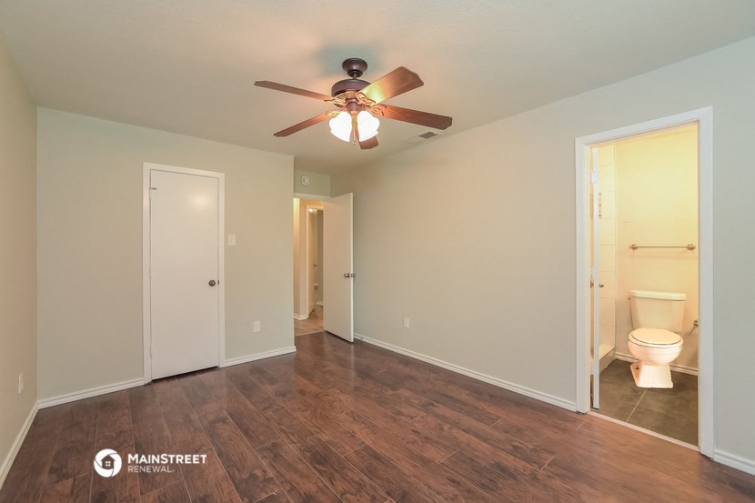 a living room with a ceiling fan and a toilet