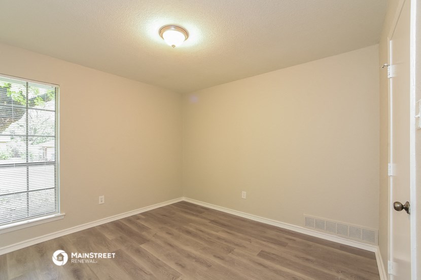 the interior of an empty room with wood flooring and a window