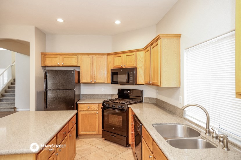 a kitchen with wooden cabinets and black appliances and a sink