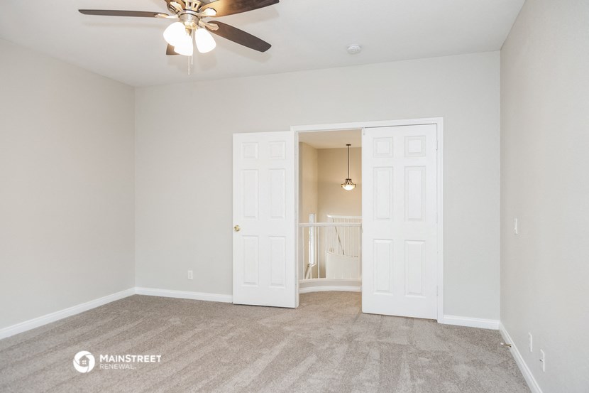 the living room of an empty home with a ceiling fan