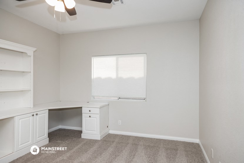 a bedroom with a desk and a window