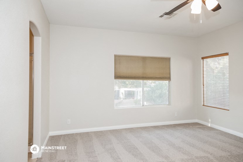 an empty living room with a window and a ceiling fan