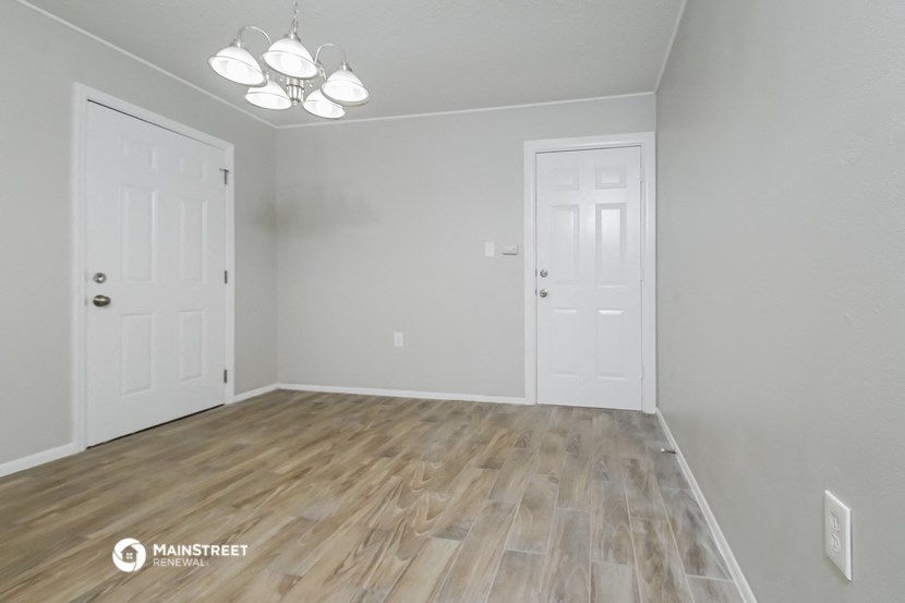 the spacious living room with wood flooring and white walls