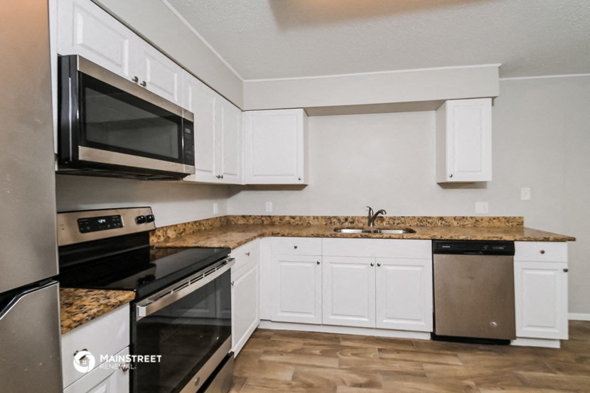 a kitchen with white cabinets and black appliances
