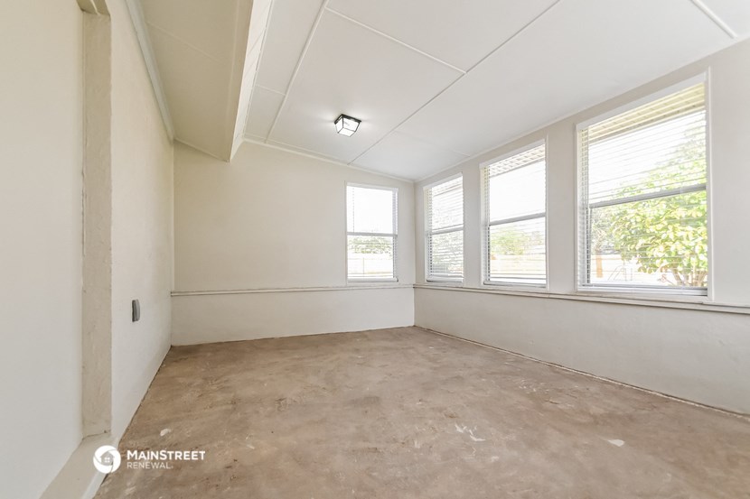 an empty room with three windows and a cement floor