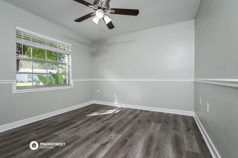an empty room with a window and a ceiling fan
