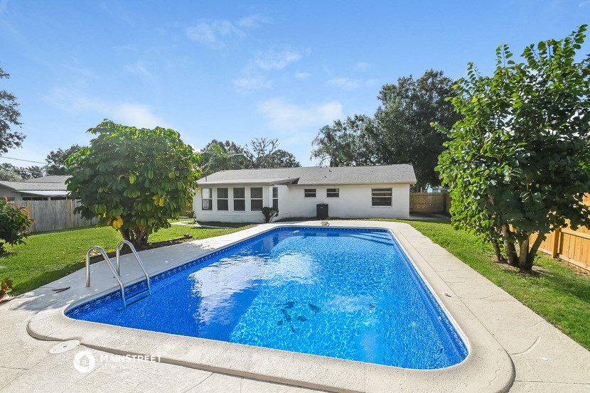 a large pool in a backyard with a house in the background