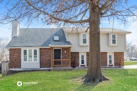 a brick house with a large tree in front of it