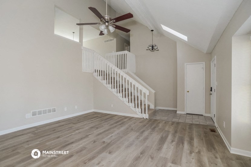 the spacious living room has a ceiling fan and hardwood floors