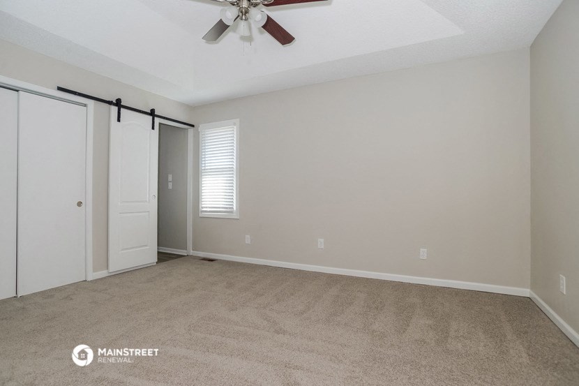 the spacious living room with closet and ceiling fan