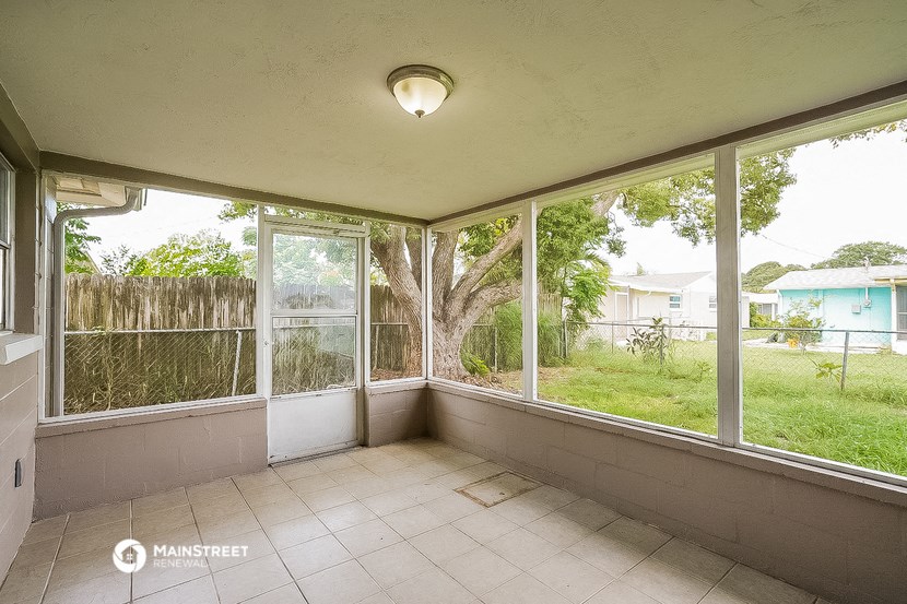 a porch with large windows and a tiled floor