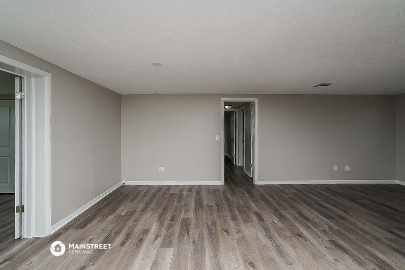 an empty living room with wood flooring and white walls