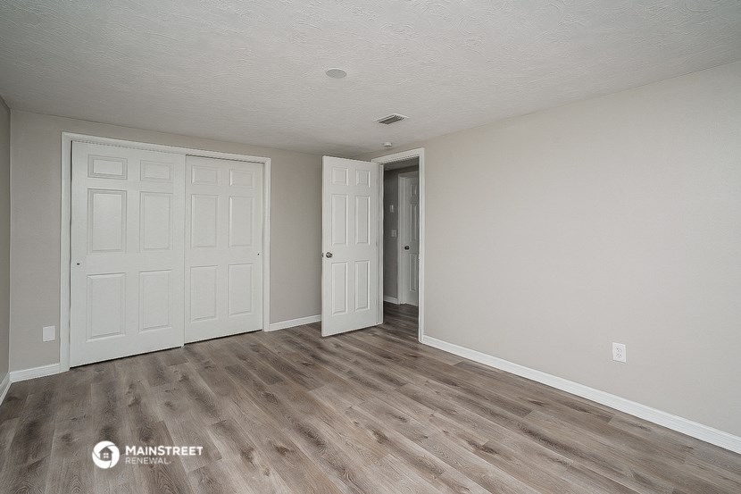 the living room of an apartment with white walls and wood floors
