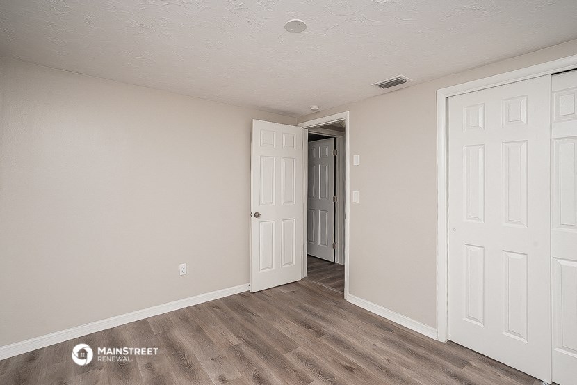 the living room of an apartment with white walls and wood floors