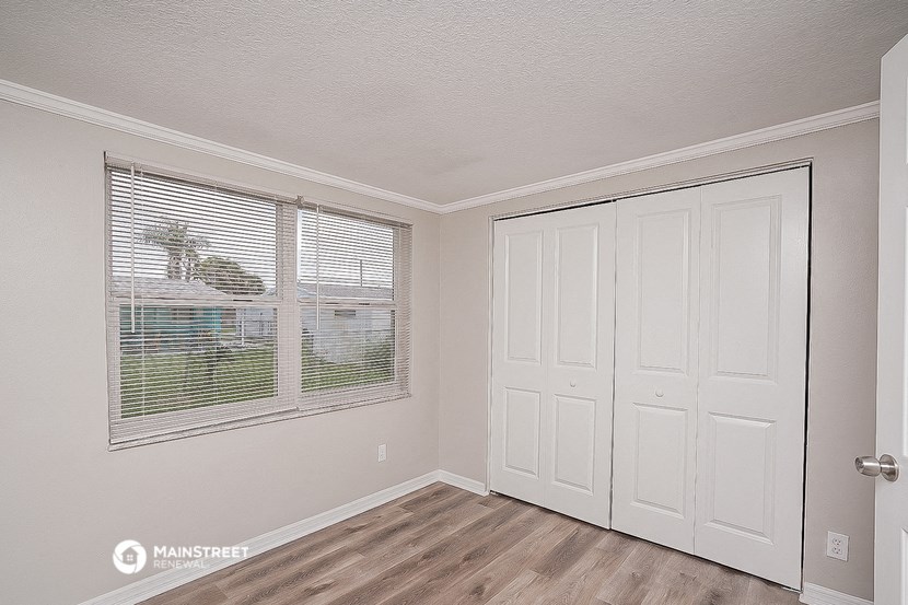 a bedroom with a large window and a door to a closet