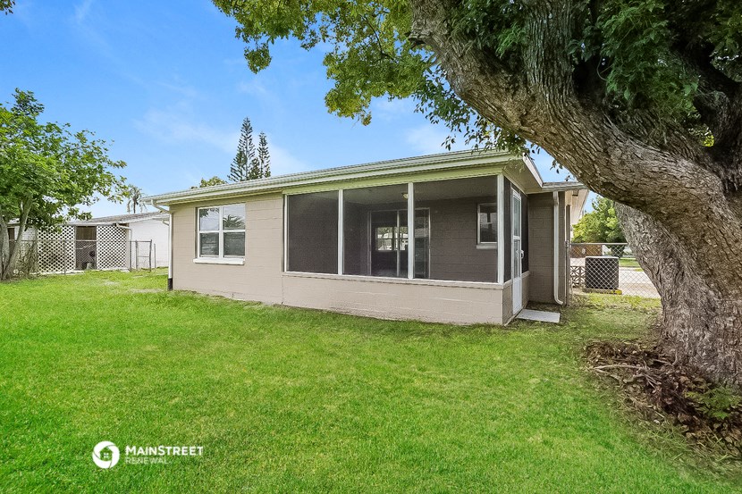 a small tan house with a large tree in front of it