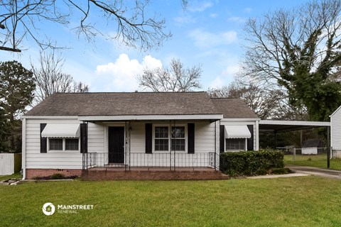 a small white house with a porch and a lawn