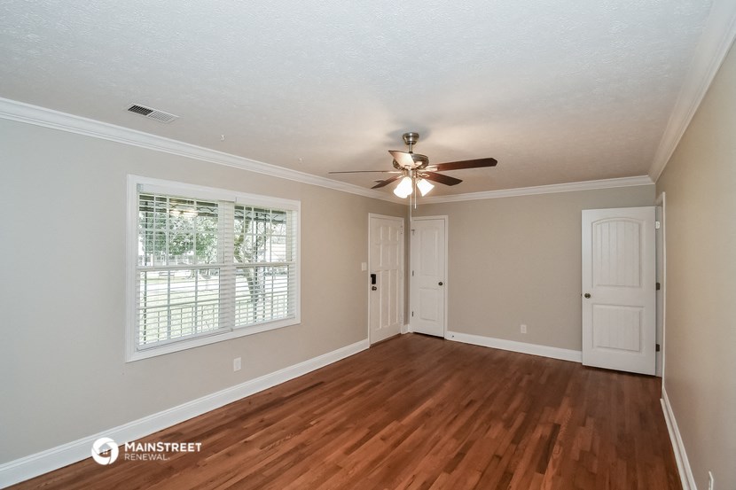 an empty living room with a ceiling fan and a window