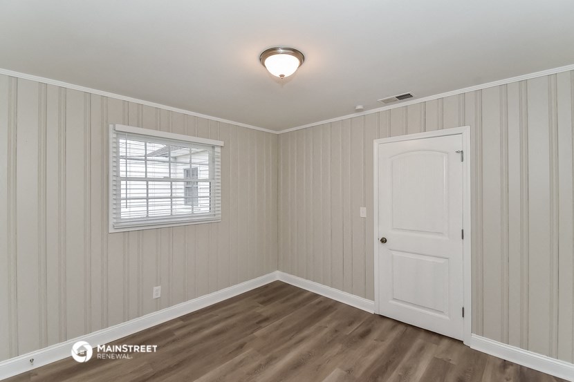 the bedroom of a house with a white door and a window