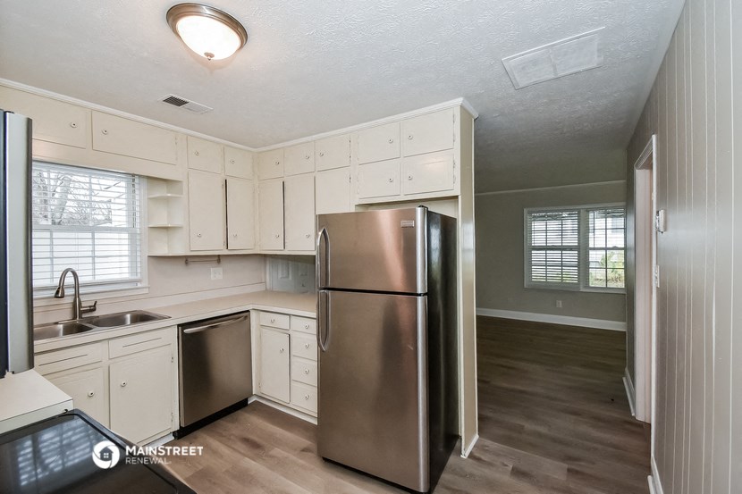 a kitchen with white cabinets and a stainless steel refrigerator