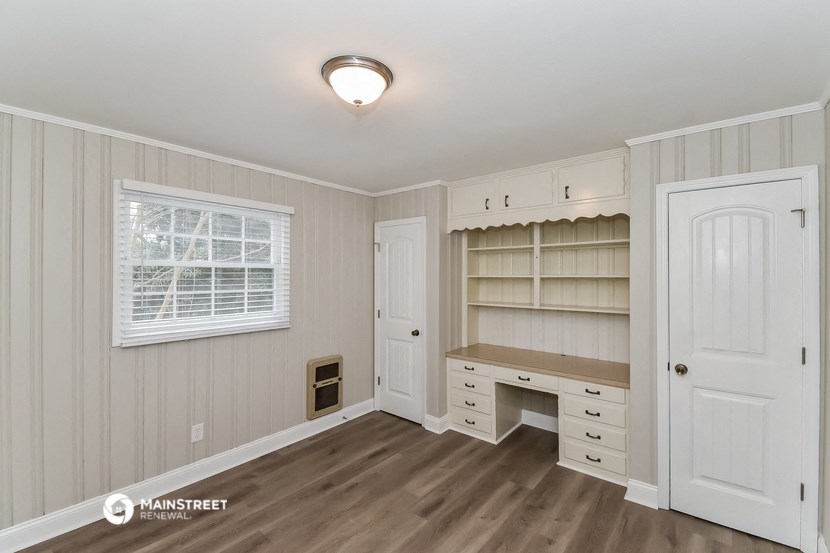a bedroom with a desk and a closet and a window