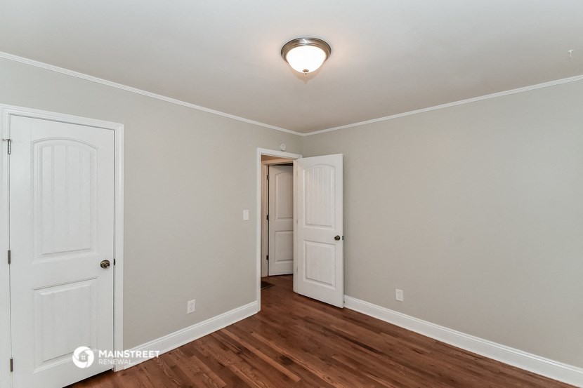 a bedroom with two doors and a door to a hallway