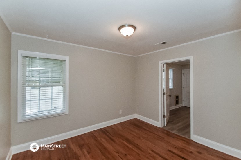 the living room of a house with a hardwood floor and a window