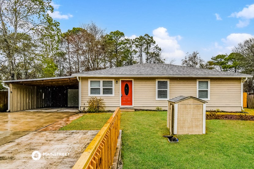a yellow house with a red door and a wooden fence