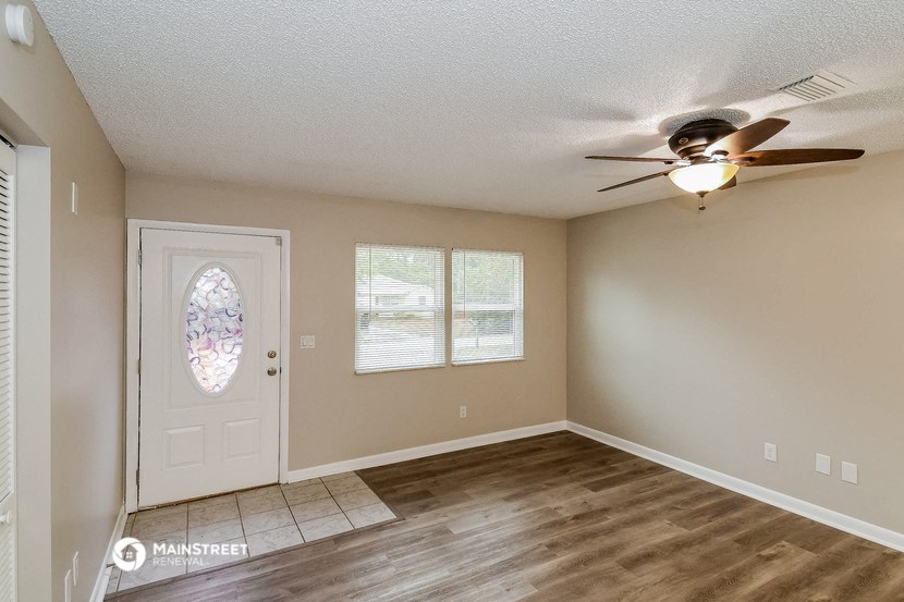 an empty living room with a ceiling fan and a door