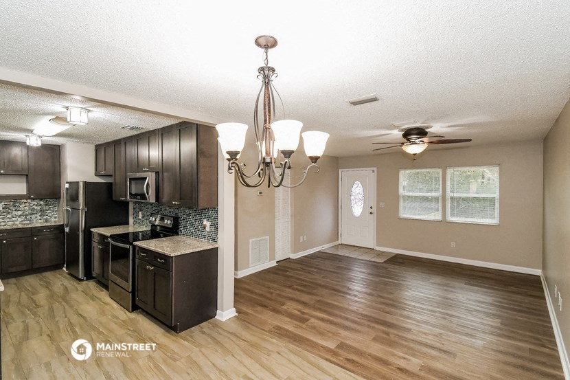 an empty kitchen and dining room with wood flooring and a chandelier