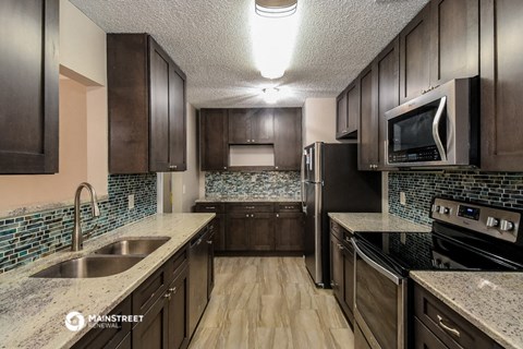 a kitchen with dark wood cabinets and granite counter tops and a sink