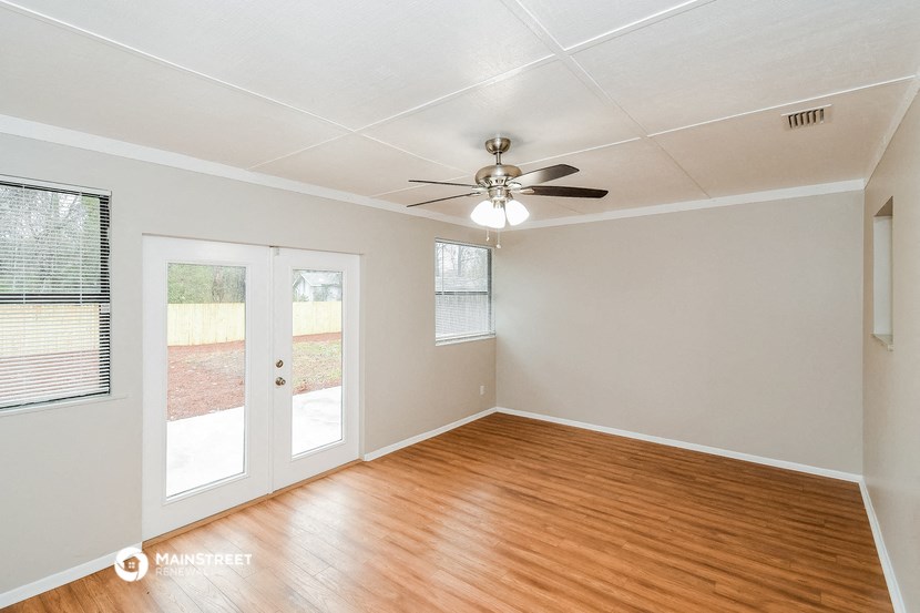 an empty living room with wood floors and a ceiling fan