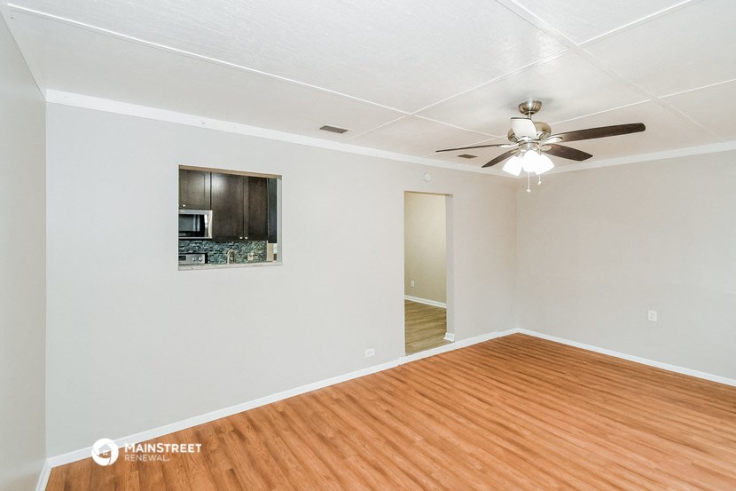 an empty living room with wood flooring and a ceiling fan