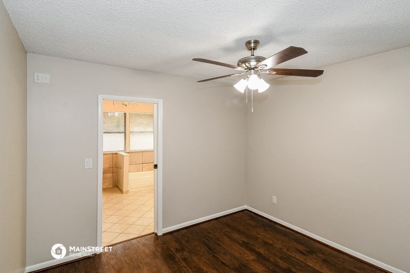 a living room with a ceiling fan and a door to a kitchen