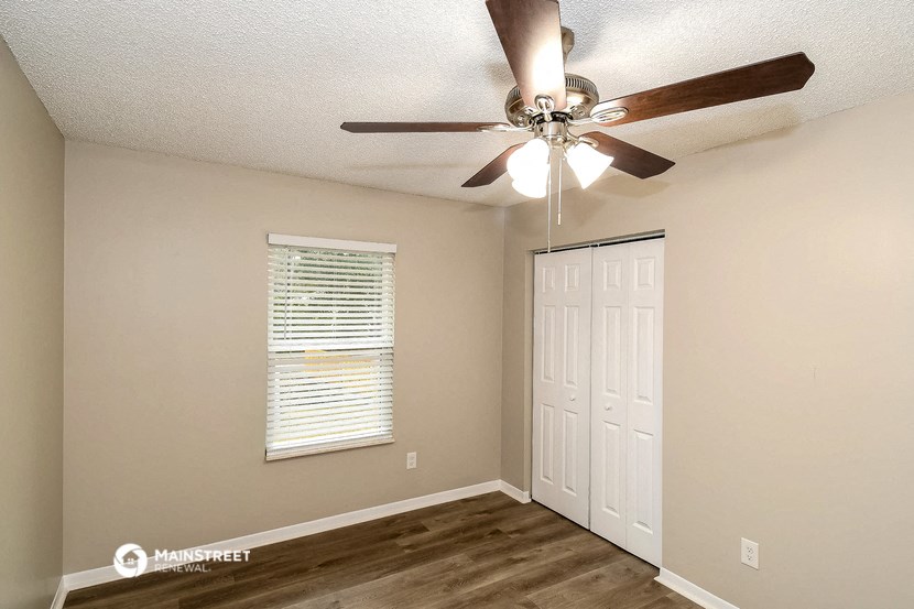 a bedroom with a ceiling fan and a door to a closet