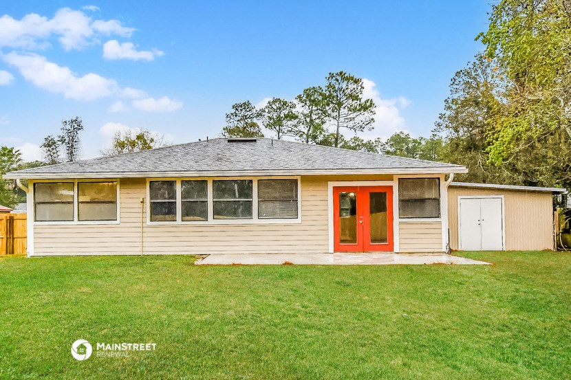 a small white house with a red door on a lawn