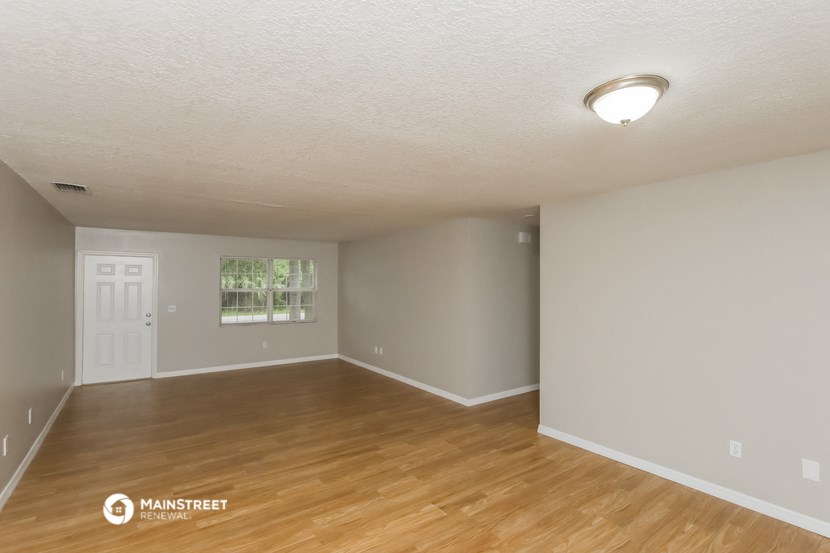 the spacious living room with hardwood flooring and white walls