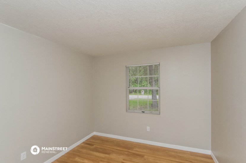 a bedroom with a window and a wooden floor