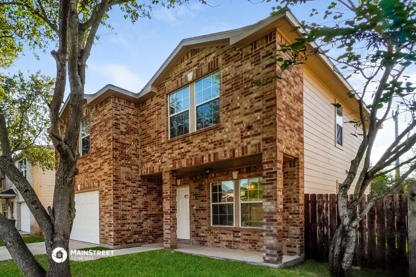 the front of a brick house with a white garage and a tree